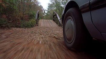 Movie still from “Road Trip” (2000), directed by Todd Phillips – A truck driving down a dirt road in a wooded area; Wide shot, High angle