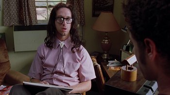 Movie still from “Road Trip” (2000), directed by Todd Phillips – A man sitting at a table with a book in front of him; Medium shot, Over the shoulder angle