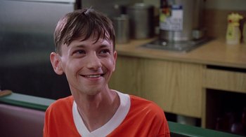 Movie still from “Road Trip” (2000), directed by Todd Phillips – A man in an orange shirt smiling for the camera; Close Up shot, Low angle