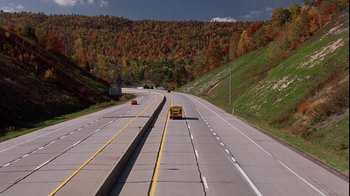 Movie still from “Road Trip” (2000), directed by Todd Phillips – A school bus driving down a highway in the middle of the day; Extreme Wide shot, High angle
