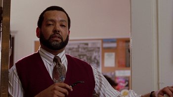 Movie still from “Road Trip” (2000), directed by Todd Phillips – A man in a red vest and a tie holding a pipe in his hand; Close Up shot, Over the shoulder angle