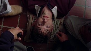 Movie still from “Road Trip” (2000), directed by Todd Phillips – A man laying on the ground holding a pillow; Close Up shot, Overhead angle
