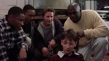 Movie still from “Road Trip” (2000), directed by Todd Phillips – A group of people sitting around a room together; Medium shot, High angle