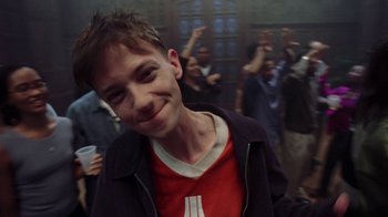 Movie still from “Road Trip” (2000), directed by Todd Phillips – A young man smiling for the camera with a crowd of people in the background; Close Up shot, Low angle