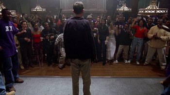 Movie still from “Road Trip” (2000), directed by Todd Phillips – A man standing in front of a group of people; Wide shot, High angle