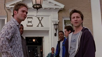 Movie still from “Road Trip” (2000), directed by Todd Phillips – A group of young men standing next to each other in front of a building; Medium shot, Low angle