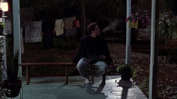 Movie still from “Road Trip” (2000), directed by Todd Phillips – A man sitting on top of a wooden bench; Wide shot, Low angle