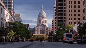 Movie still from “Road Trip” (2000), directed by Todd Phillips – A school bus driving down the street in front of a large building; Extreme Wide shot, Low angle