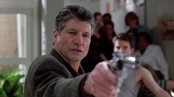 Movie still from “Road Trip” (2000), directed by Todd Phillips – A person holding a gun in a room; Close Up shot, Over the shoulder angle