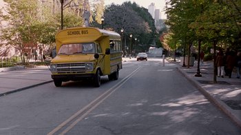 Movie still from “Road Trip” (2000), directed by Todd Phillips – A school bus driving down a street next to trees; Extreme Wide shot, High angle