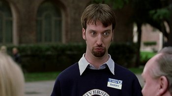 Movie still from “Road Trip” (2000), directed by Todd Phillips – A man in a sweater with a name tag on his shirt; Close Up shot, Low angle