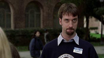 Movie still from “Road Trip” (2000), directed by Todd Phillips – A man in a blue sweater with a name tag on his shirt; Close Up shot, Low angle