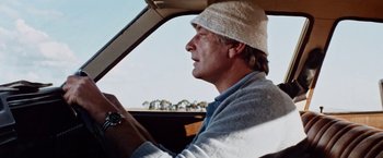Movie still from “Road Games” (1981), directed by Richard Franklin – A man driving a car wearing a white hat; Close Up shot, Low angle