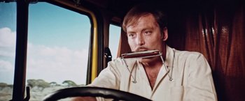 Movie still from “Road Games” (1981), directed by Richard Franklin – A man in a white shirt driving a yellow truck; Close Up shot, Low angle