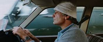 Movie still from “Road Games” (1981), directed by Richard Franklin – A man driving a car wearing a white hat; Close Up shot, Low angle