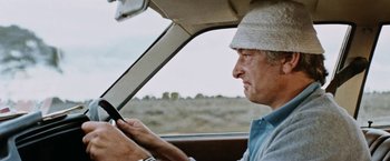 Movie still from “Road Games” (1981), directed by Richard Franklin – An older man driving a car while looking at his cell phone; Close Up shot, Low angle