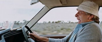 Movie still from “Road Games” (1981), directed by Richard Franklin – A man driving a car on a dirt road; Close Up shot, Low angle