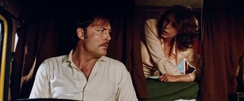 Movie still from “Road Games” (1981), directed by Richard Franklin – A man and a woman sitting on a bed in front of each other; Medium shot, Low angle