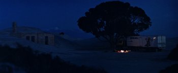 Movie still from “Road Games” (1981), directed by Richard Franklin – A fire in the middle of the night near a tree; Extreme Wide shot, Low angle