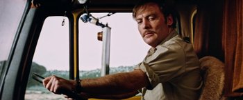 Movie still from “Road Games” (1981), directed by Richard Franklin – A man driving a yellow truck with his hand on the steering wheel; Close Up shot, Low angle