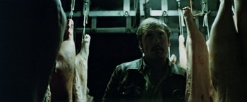 Movie still from “Road Games” (1981), directed by Richard Franklin – A man standing next to a bunch of meat hanging; Close Up shot, Low angle