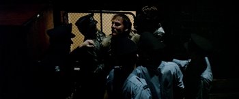 Movie still from “Road Games” (1981), directed by Richard Franklin – A group of men standing around a fence; Medium shot, High angle