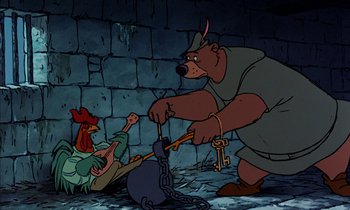 Movie still from “Robin Hood” (1973), directed by David Hand – A man and a woman chained to a brick wall; Wide shot, High angle