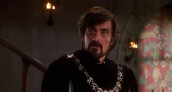 Movie still from “Robin Hood: Men in Tights” (1993), directed by Mel Brooks – A person with a beard wearing a suit; Close Up shot, Over the shoulder angle
