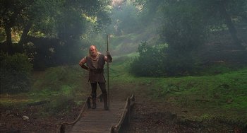 Movie still from “Robin Hood: Men in Tights” (1993), directed by Mel Brooks – A man dressed as a viking holding a spear on top of a wooden bridge; Wide shot, Low angle