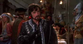 Movie still from “Robin Hood: Men in Tights” (1993), directed by Mel Brooks – A man with a beard wearing a black and silver outfit; Medium shot, Over the shoulder angle