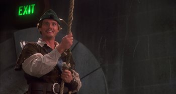 Movie still from “Robin Hood: Men in Tights” (1993), directed by Mel Brooks – A man holding a rope and smiling for the camera; Medium shot, Low angle