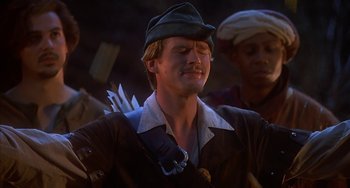 Movie still from “Robin Hood: Men in Tights” (1993), directed by Mel Brooks – A young man wearing a hat and holding a bow and arrow; Close Up shot, Low angle