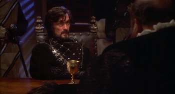Movie still from “Robin Hood: Men in Tights” (1993), directed by Mel Brooks – A man sitting at a table with a glass of wine; Medium shot, Over the shoulder angle