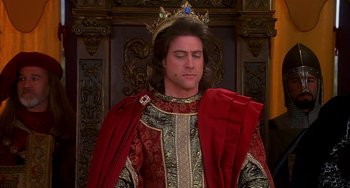 Movie still from “Robin Hood: Men in Tights” (1993), directed by Mel Brooks – A man wearing a red robe and a gold crown; Close Up shot, Low angle