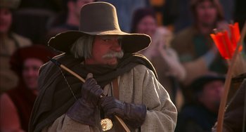 Movie still from “Robin Hood: Men in Tights” (1993), directed by Mel Brooks – A man with a long beard wearing a hat and holding a stick; Close Up shot, Low angle