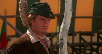 Movie still from “Robin Hood: Men in Tights” (1993), directed by Mel Brooks – A man wearing a green hat and a brown jacket; Close Up shot, Low angle