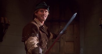 Movie still from “Robin Hood: Men in Tights” (1993), directed by Mel Brooks – A man dressed as robin hood holding a sword; Medium shot, Low angle