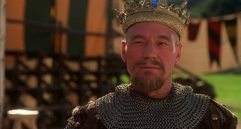 Movie still from “Robin Hood: Men in Tights” (1993), directed by Mel Brooks – A man wearing a chain mail outfit and wearing a crown; Close Up shot, Low angle