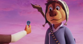 Movie still from “Rock Dog 2: Rock Around the Park” (2021), directed by Mark Baldo – A person is holding a guitar pick in front of a cartoon character; Close Up shot, Over the shoulder angle