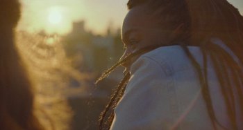 Movie still from “Rocks” (2019), directed by Sarah Gavron – A person with long dreadlocks in the sunlight; Close Up shot, Low angle