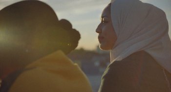 Movie still from “Rocks” (2019), directed by Sarah Gavron – A woman wearing a headscarf is standing next to another woman; Close Up shot, Low angle