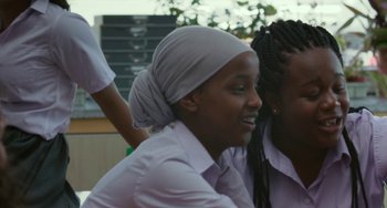Movie still from “Rocks” (2019), directed by Sarah Gavron – A woman wearing a head scarf is sitting next to another woman; Close Up shot, Over the shoulder angle