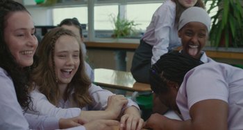 Movie still from “Rocks” (2019), directed by Sarah Gavron – A group of people sitting in a room; Medium shot, Over the shoulder angle
