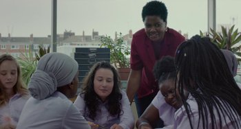 Movie still from “Rocks” (2019), directed by Sarah Gavron – A group of young people sitting around a table; Medium shot, Over the shoulder angle