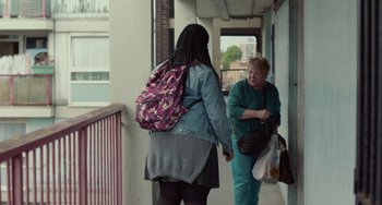 Movie still from “Rocks” (2019), directed by Sarah Gavron – Two women walking down a hallway with bags of luggage; Wide shot, Over the shoulder angle