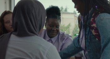 Movie still from “Rocks” (2019), directed by Sarah Gavron – A group of people sitting around a table; Medium shot, Over the shoulder angle