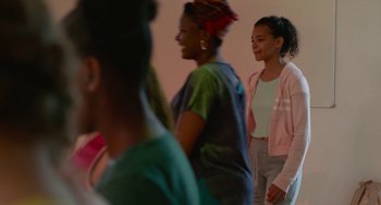 Movie still from “Rocks” (2019), directed by Sarah Gavron – A group of women standing next to each other in a room; Medium shot, Over the shoulder angle