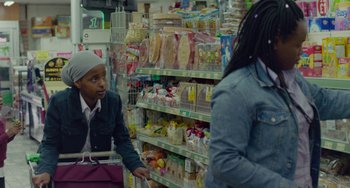 Movie still from “Rocks” (2019), directed by Sarah Gavron – Two people in a grocery store talking to each other; Medium shot, Over the shoulder angle