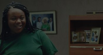 Movie still from “Rocks” (2019), directed by Sarah Gavron – A woman standing in front of a picture of herself; Close Up shot, Over the shoulder angle