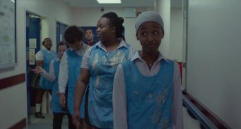 Movie still from “Rocks” (2019), directed by Sarah Gavron – A group of young people standing next to each other in a room; Medium shot, Over the shoulder angle